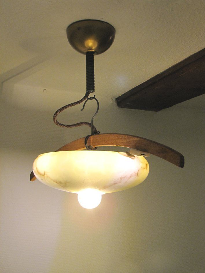 Hängende Deckenleuchte mit weißem Glasschirm und freiliegender Glühbirne in einem Zimmer
