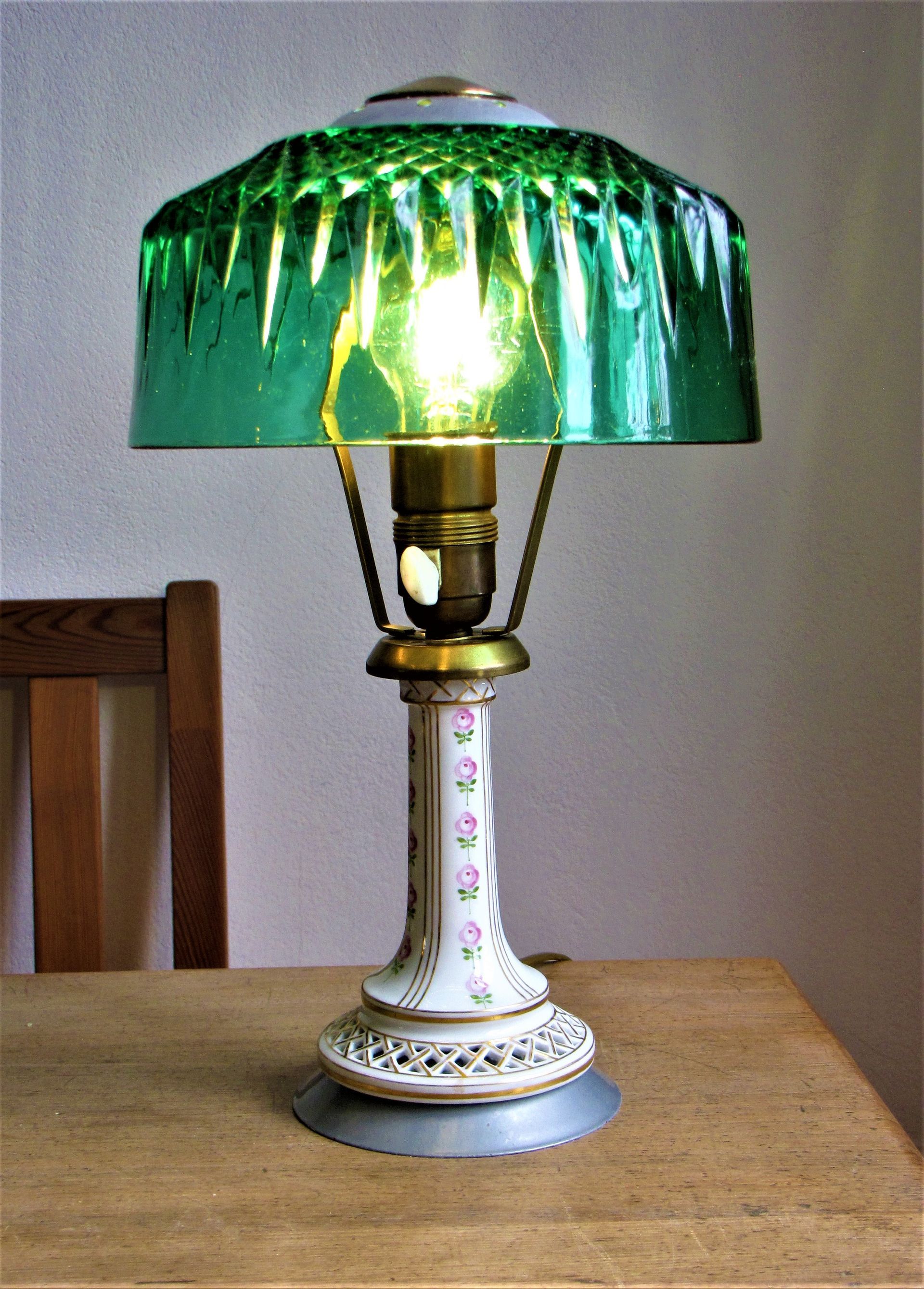 Dekorative Tischlampe mit grünem Schirm und floralem Fuß auf einem Holztisch
