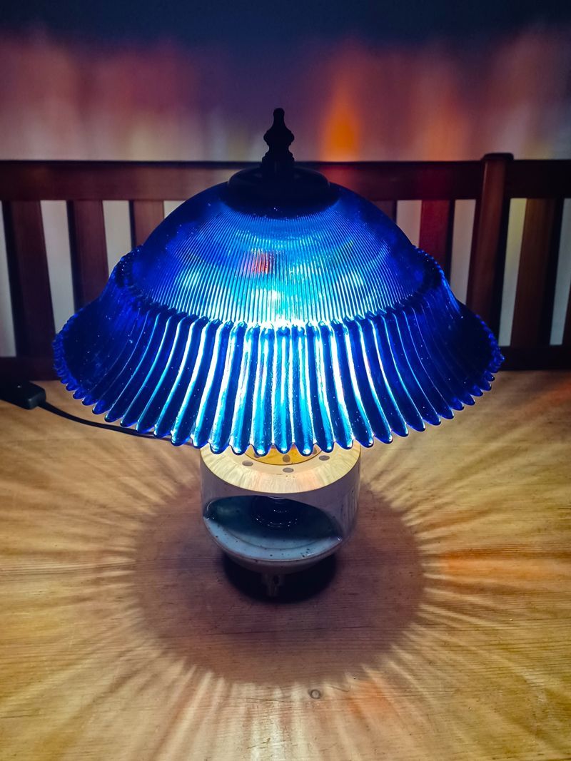 Auf einem Holztisch steht eine blaue Lampe.