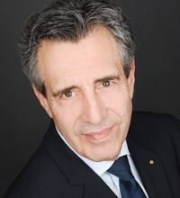 Ein Mann in Anzug und Krawatte lächelt in die Kamera.