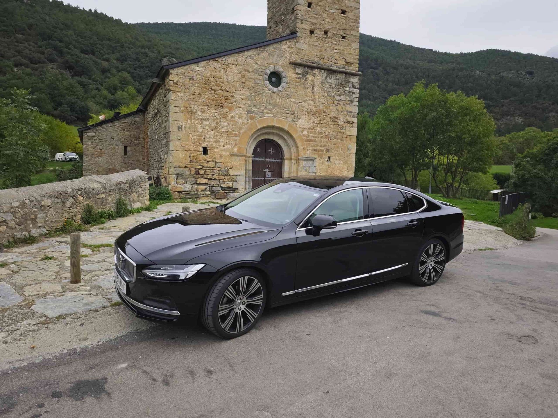 Un coche negro está aparcado delante de un edificio de piedra.