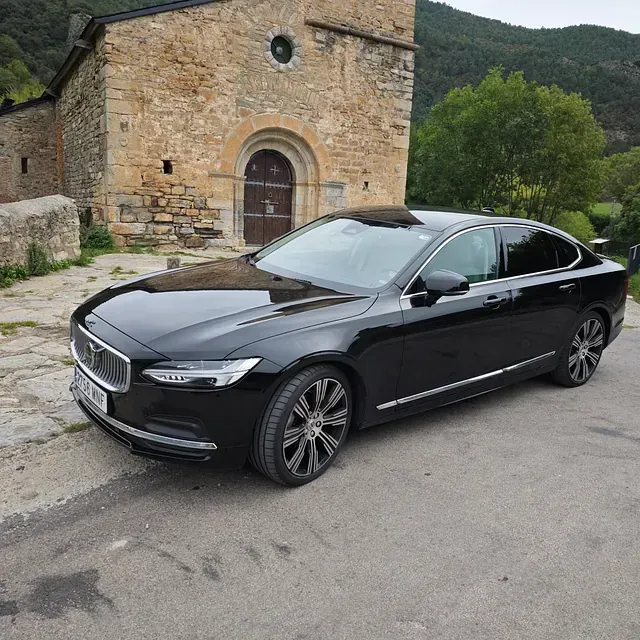 Un coche negro está aparcado delante de un edificio de piedra.