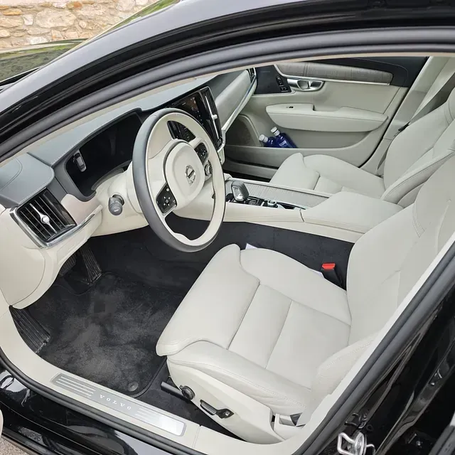 El interior de un coche negro con asientos blancos y un volante.