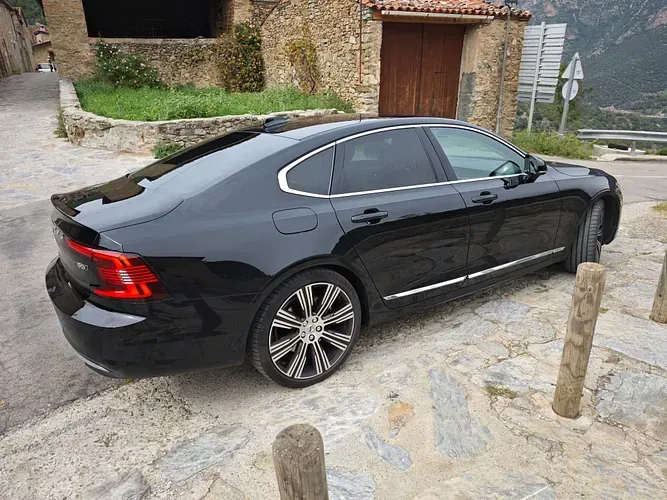 Un coche negro está aparcado delante de un edificio de piedra.