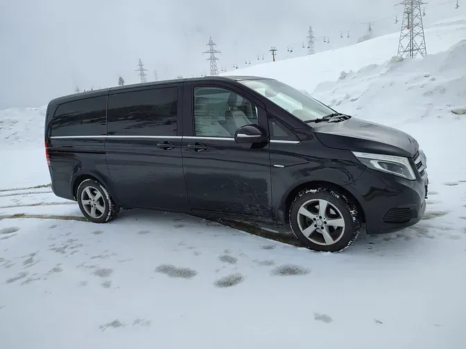 Una camioneta negra está estacionada en la nieve en una colina nevada.
