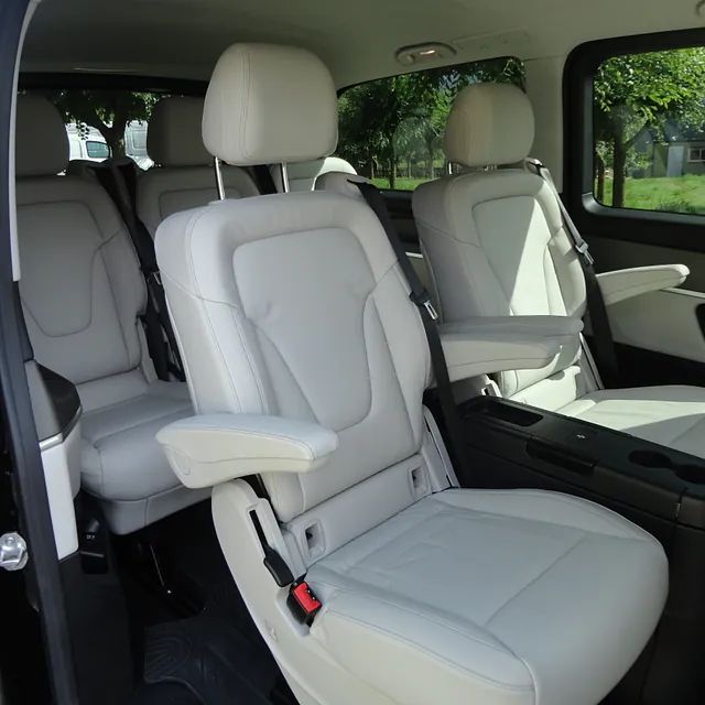 El interior de una furgoneta con asientos y reposabrazos blancos.