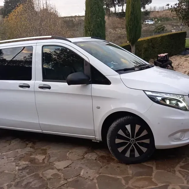 Una camioneta blanca está estacionada en un camino de piedra.