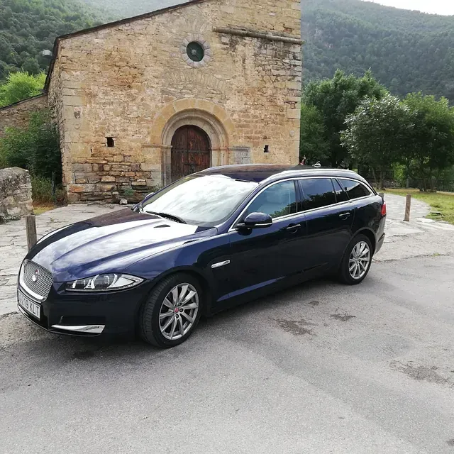 Un coche azul está aparcado delante de un edificio de piedra.