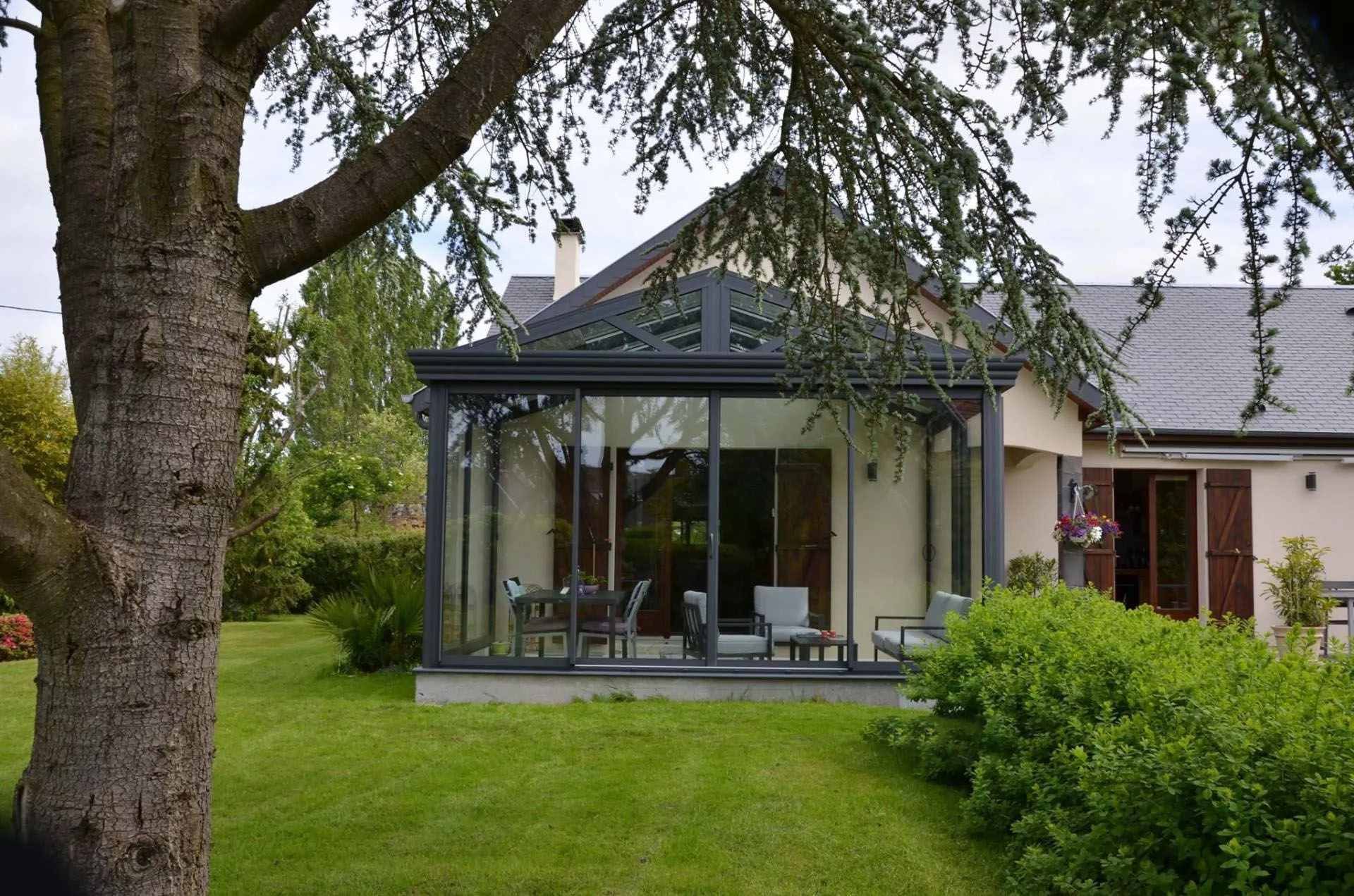 Véranda avec un toit pointu réalisé par Saforge dans un jardin