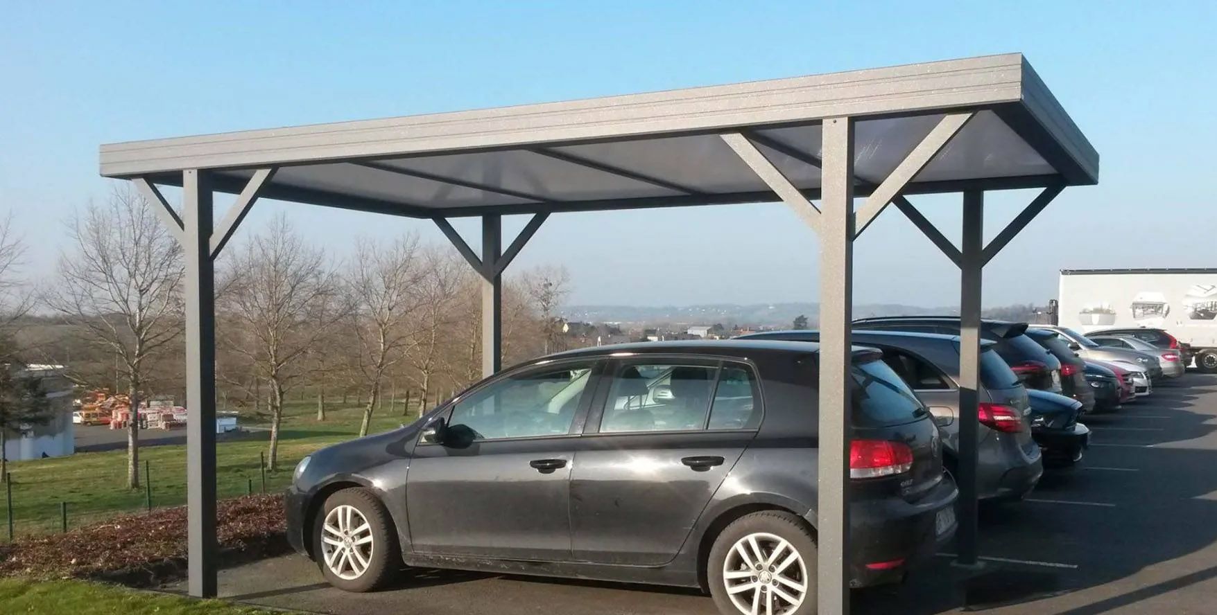 Carport en métal sur un parking avec une voiture dessous