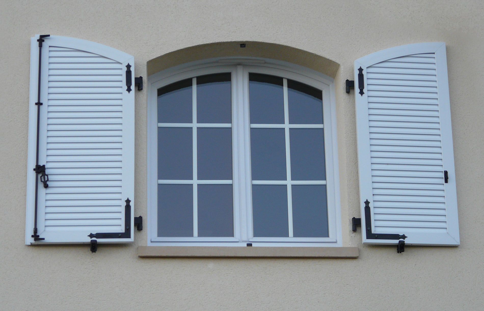 Une fenêtre arrondie avec des volets en bois