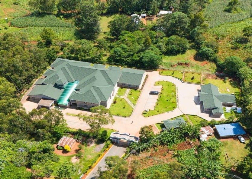 Aerial view of a complex with green roofs, surrounded by lush green vegetation.