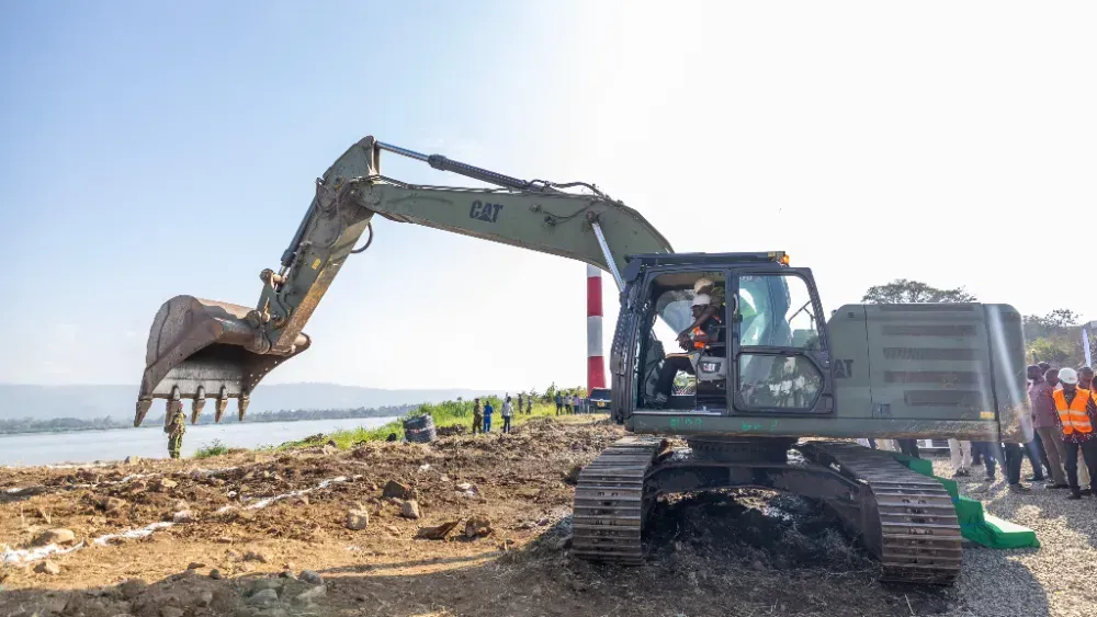 A man is driving a large excavator on a construction site.