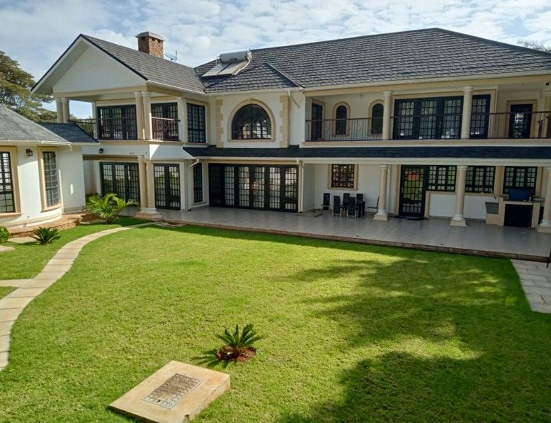 Large white house with black trim, surrounded by green lawn and a stone walkway.