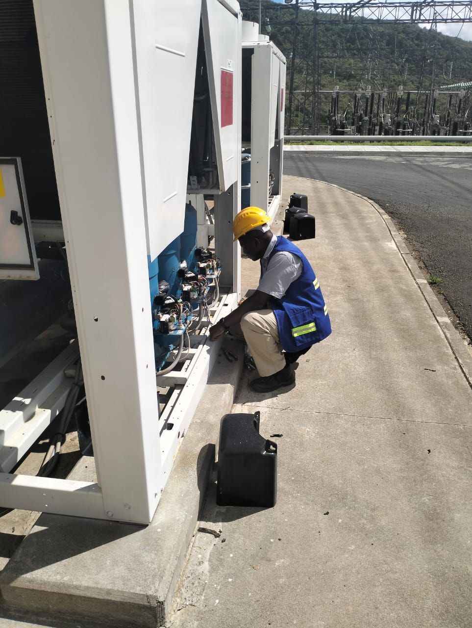 A man is working on a machine on the side of the road.