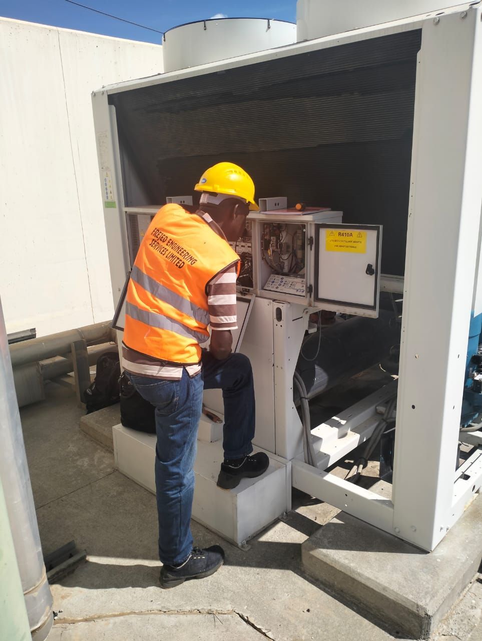 A man in an orange vest is working on a machine