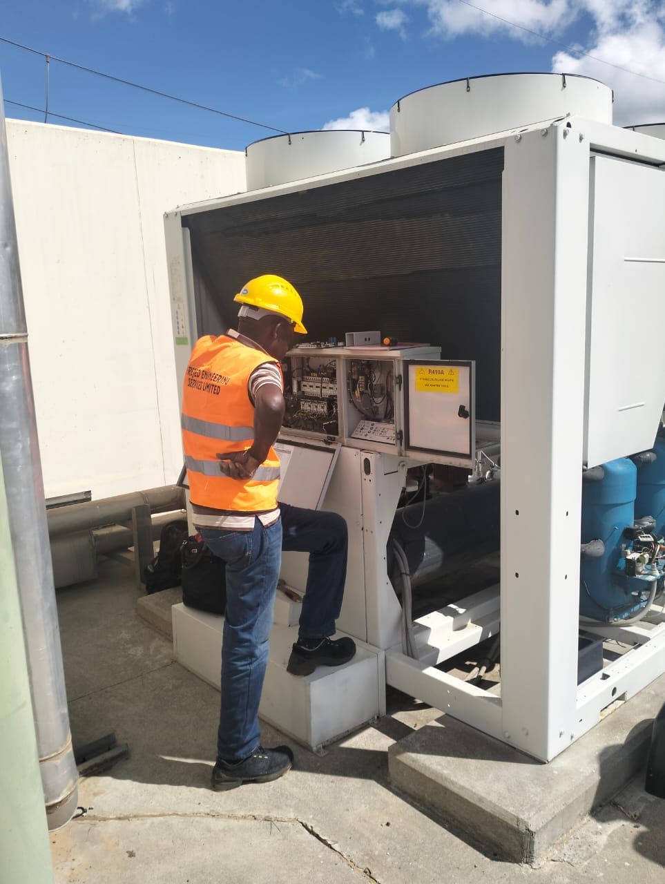A man wearing a hard hat is working on a machine.