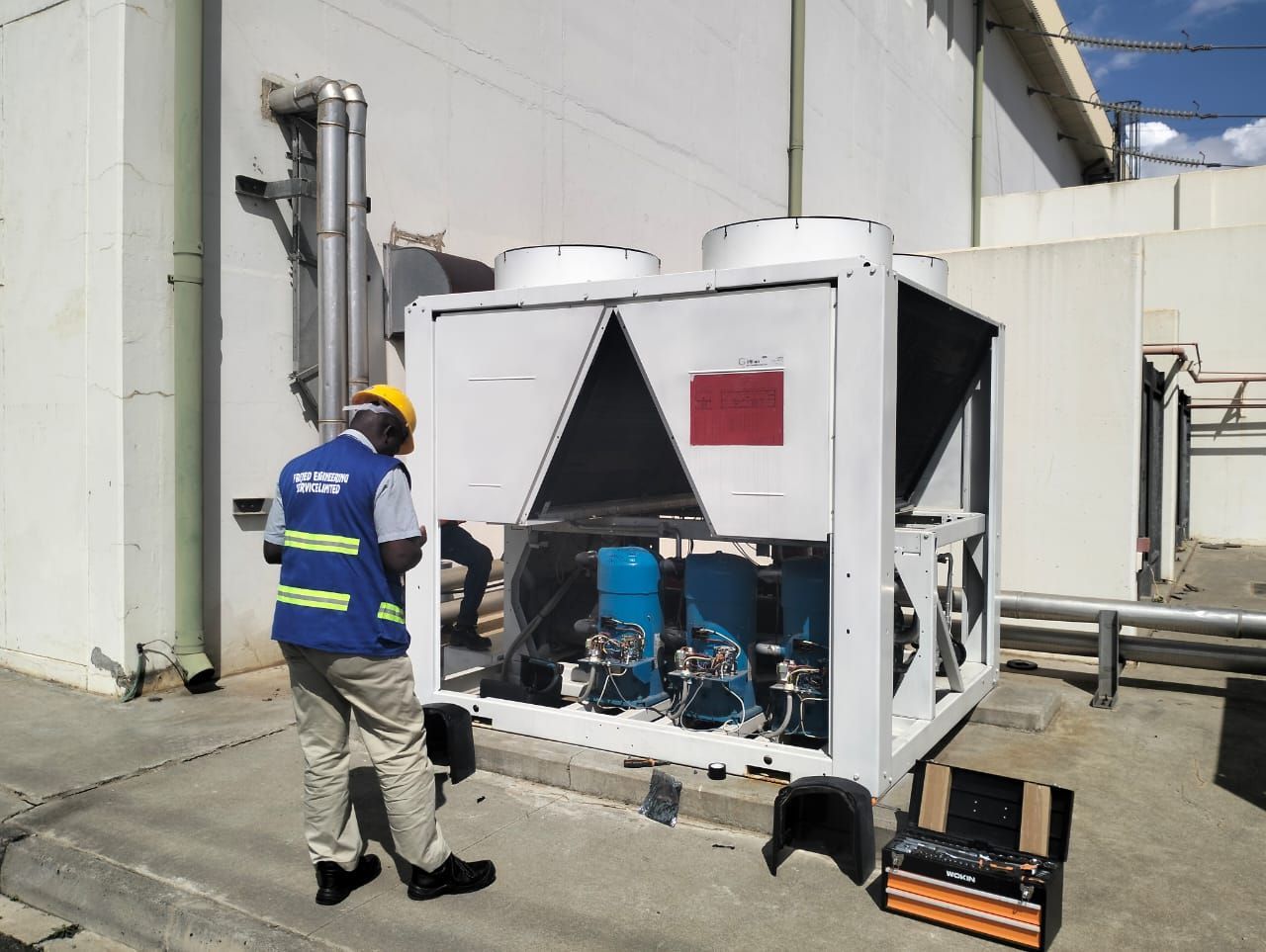 A man in a hard hat is standing next to a large white machine.
