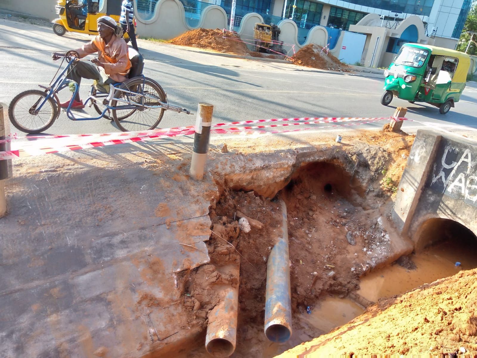 A man is riding a bike next to a hole in the ground.