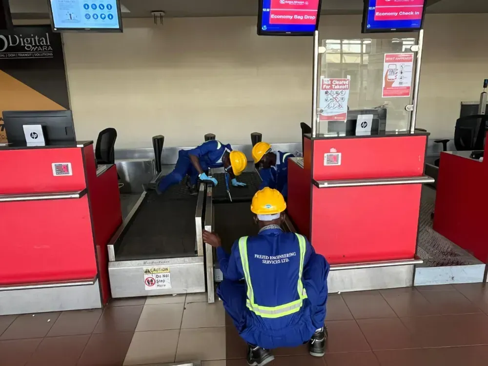 A man wearing a hard hat is working on a conveyor belt