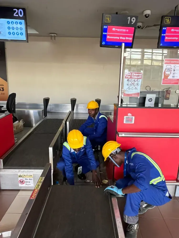 A group of men are working on a conveyor belt at an airport.