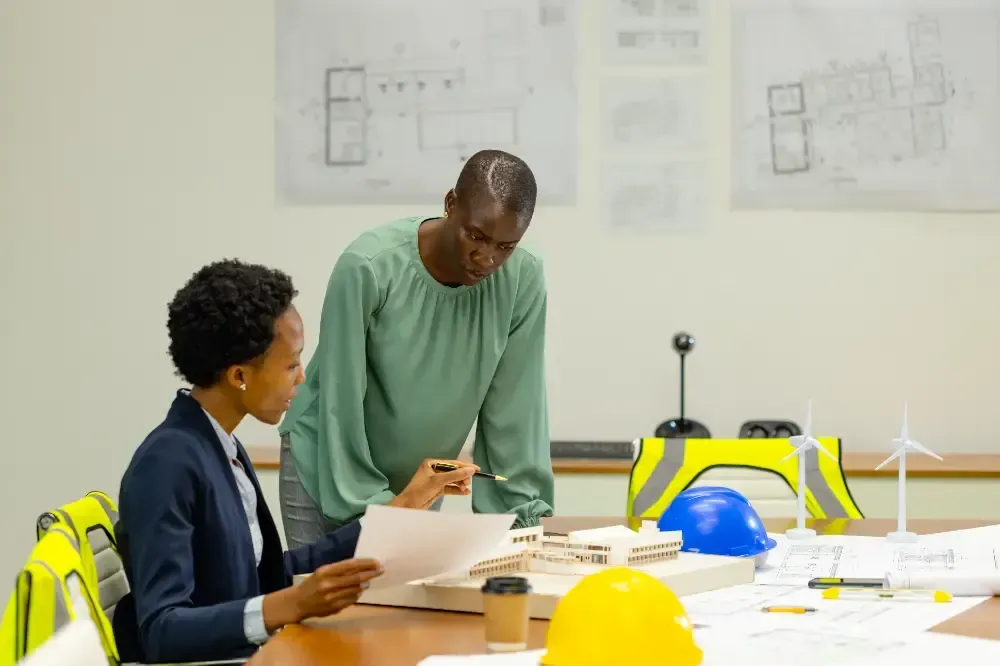Two women are sitting at a table looking at a piece of paper.
