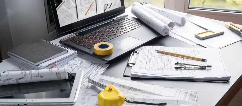 A laptop computer is sitting on top of a messy desk.