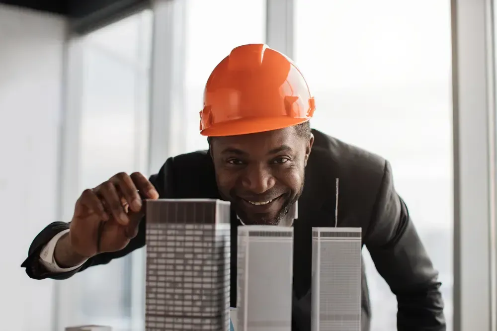 A man wearing a hard hat is looking at a model of a building.