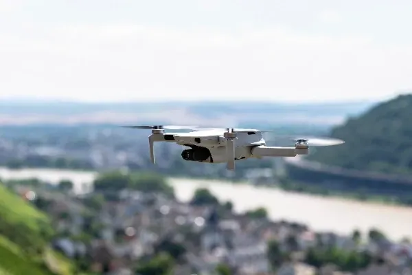 A small drone is flying over a city.