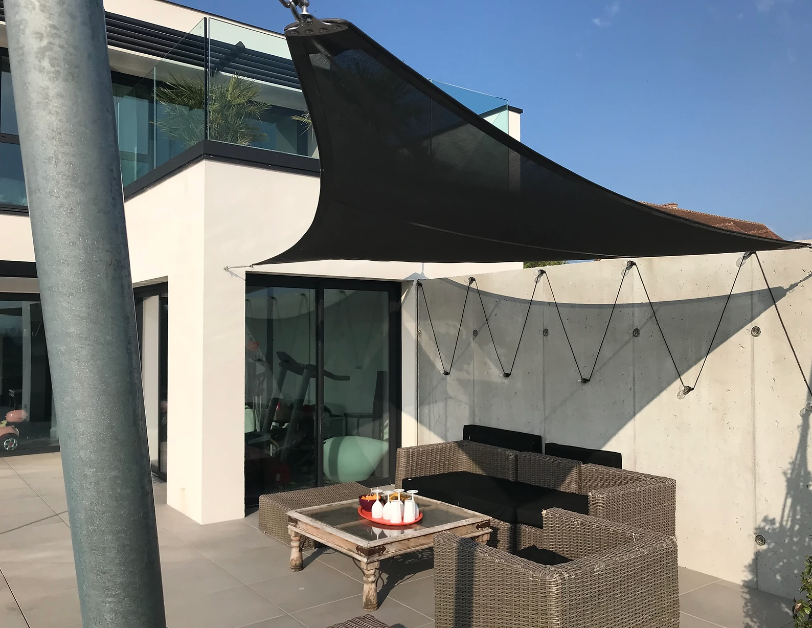 Maison contemporaine avec voile d'ombrage au-dessus d'un salon de jardin