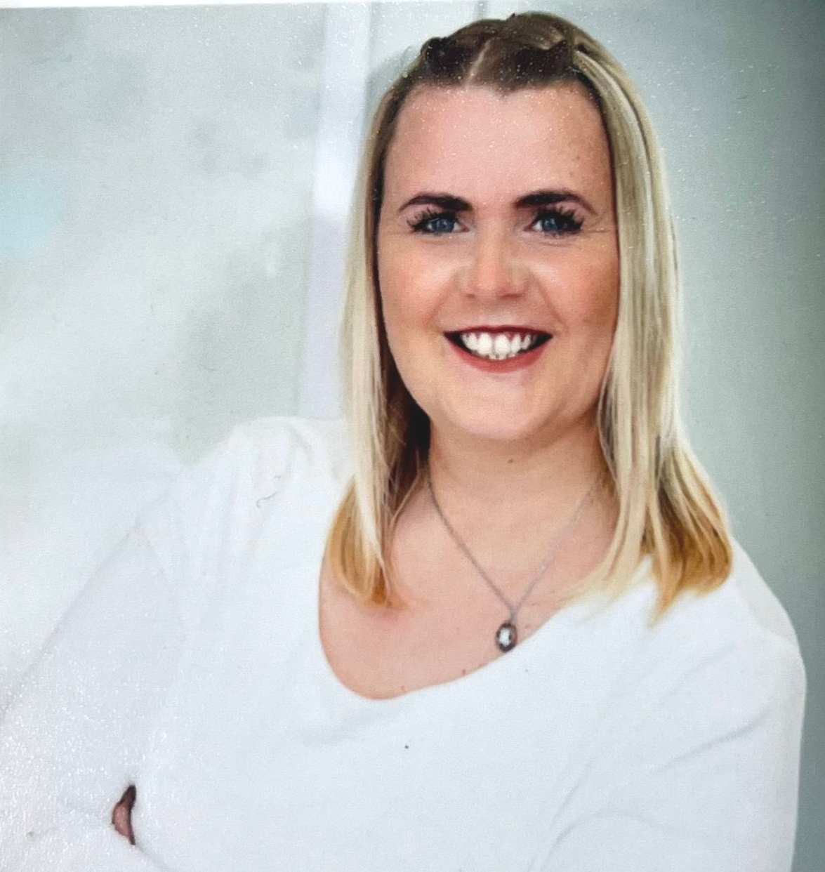 Eine Frau mit Brille und blauer Jacke steht vor einem Radio.