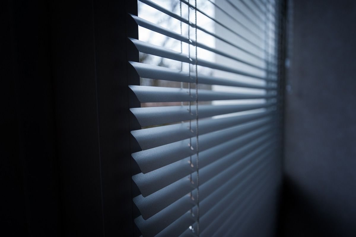 Persianas azules que dejan pasar la luz en una habitación oscura.