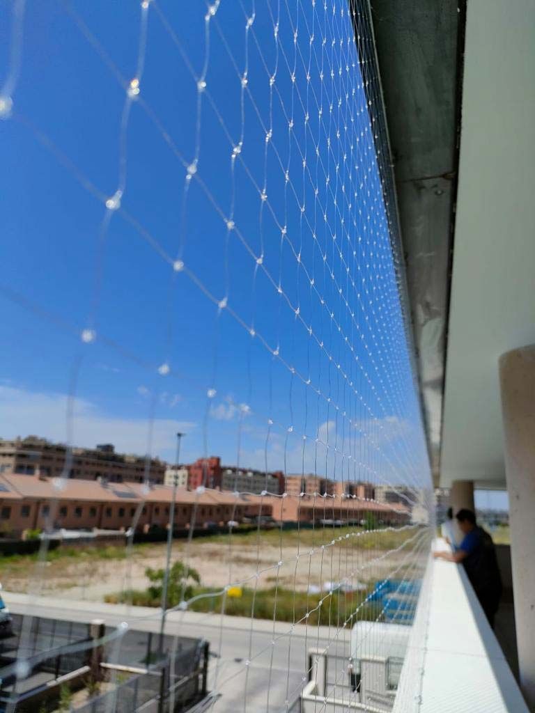 Terraza en la azotea con red de seguridad blanca con vistas a los edificios bajo un cielo azul despejado.