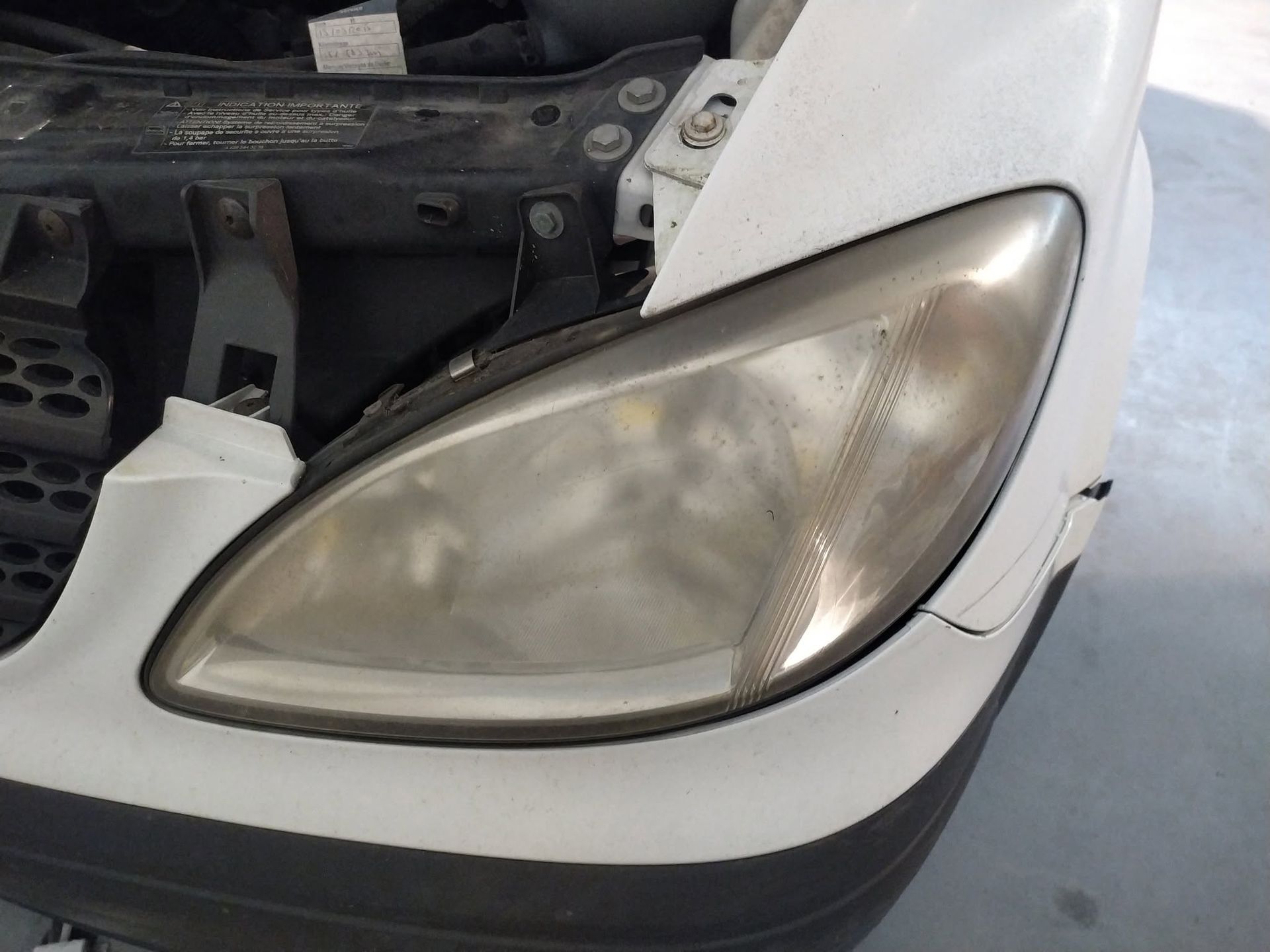 Phare terni d’une voiture, monté sur un pare-chocs blanc, avec le capot ouvert.