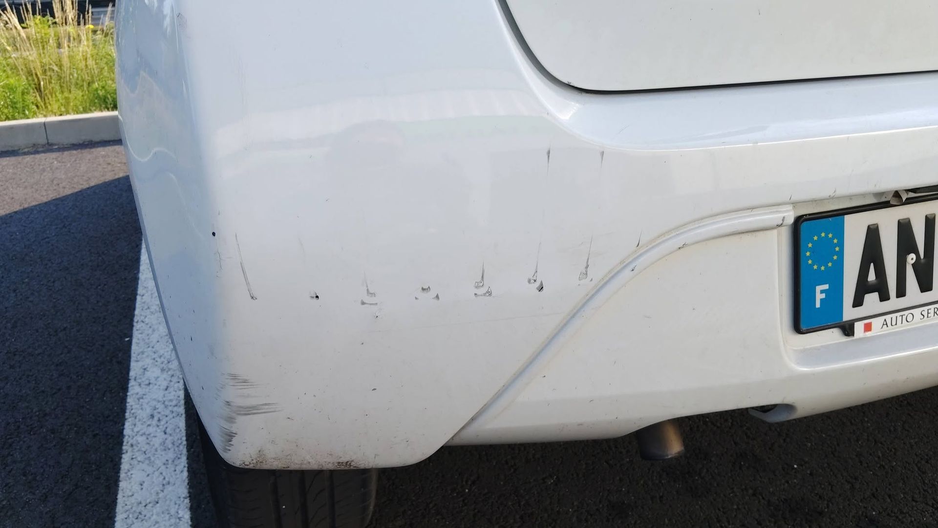 Arrière d’une voiture avec des éraflures près du pare-chocs.