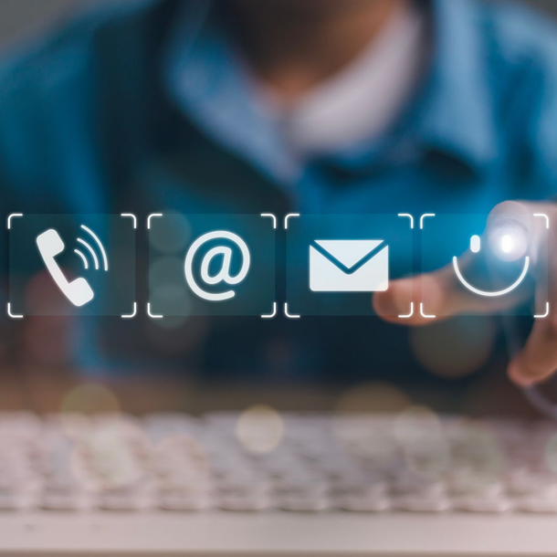 Une main touchant des icônes de contact numériques au-dessus d’un clavier.