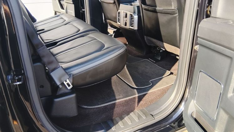 Intérieur de la banquette arrière d’un SUV avec des sièges en cuir et des tapis de sol.