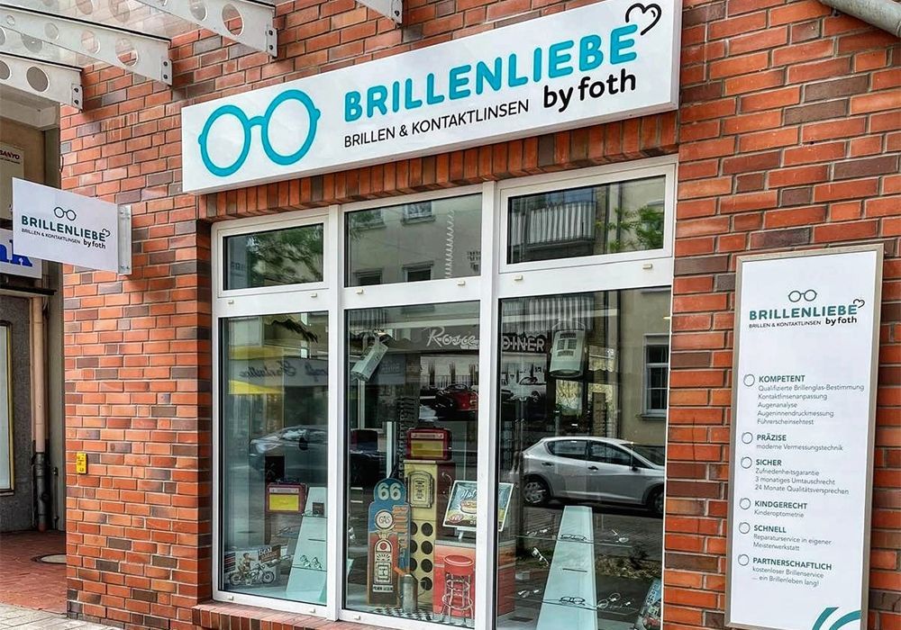 Schaufenster des Brillenliebe-Brillengeschäfts mit weißem Schild, Glastüren und Backsteinfassade