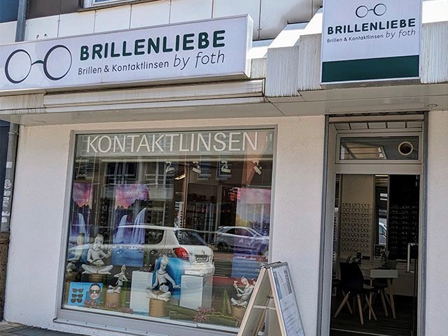 Schaufenster für Brillenliebe mit Brillenschildern und einem Kontaktlinsendisplay.