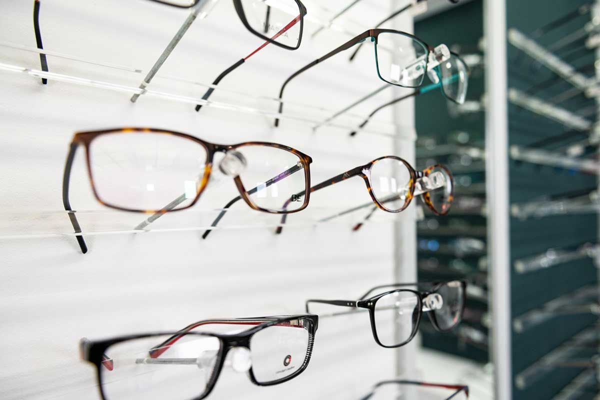 Brillen, ausgestellt an einem weißen Wandregal in einem Optikergeschäft