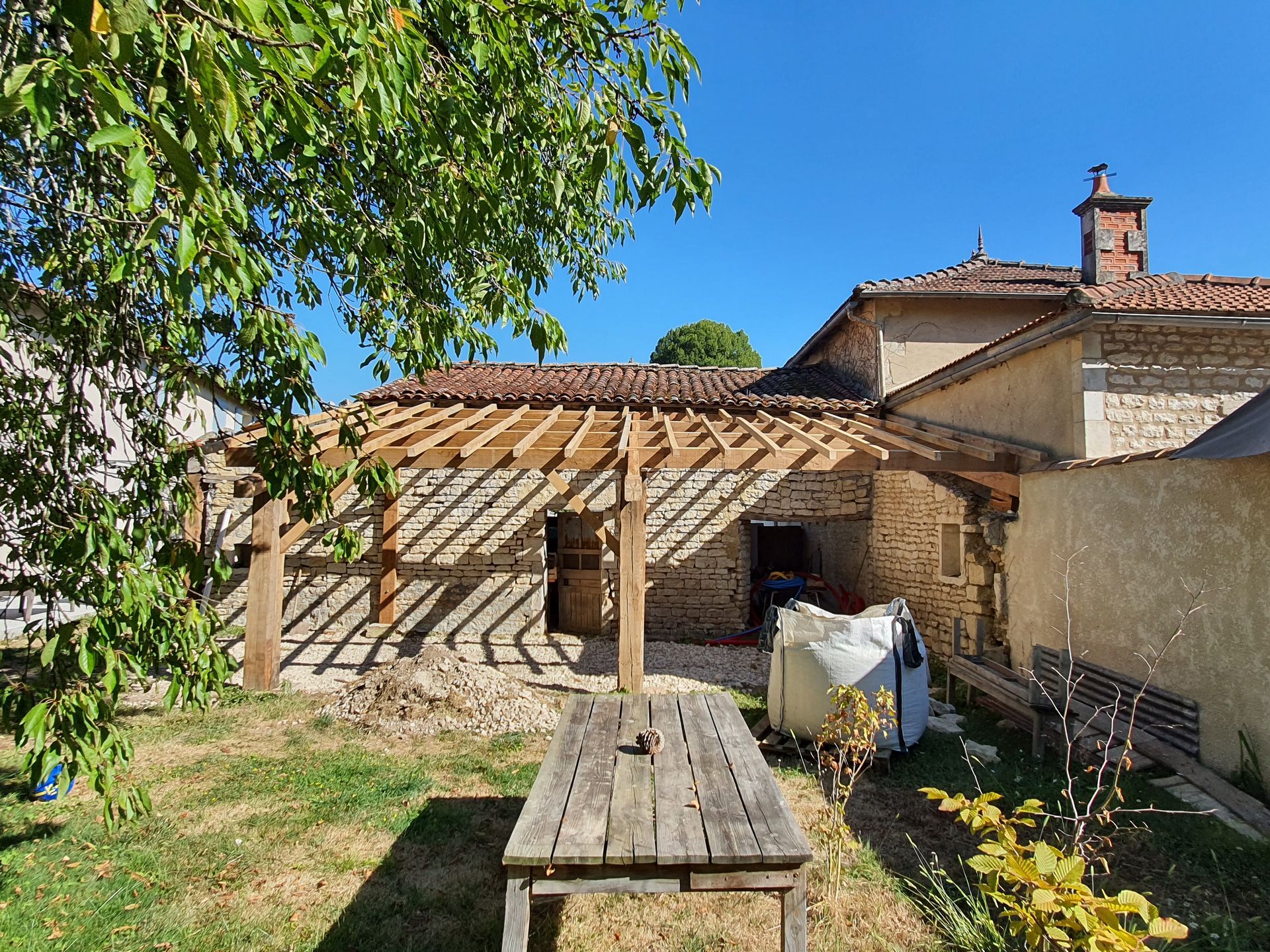 Pergola adossée à un mur avec pierres apparentes