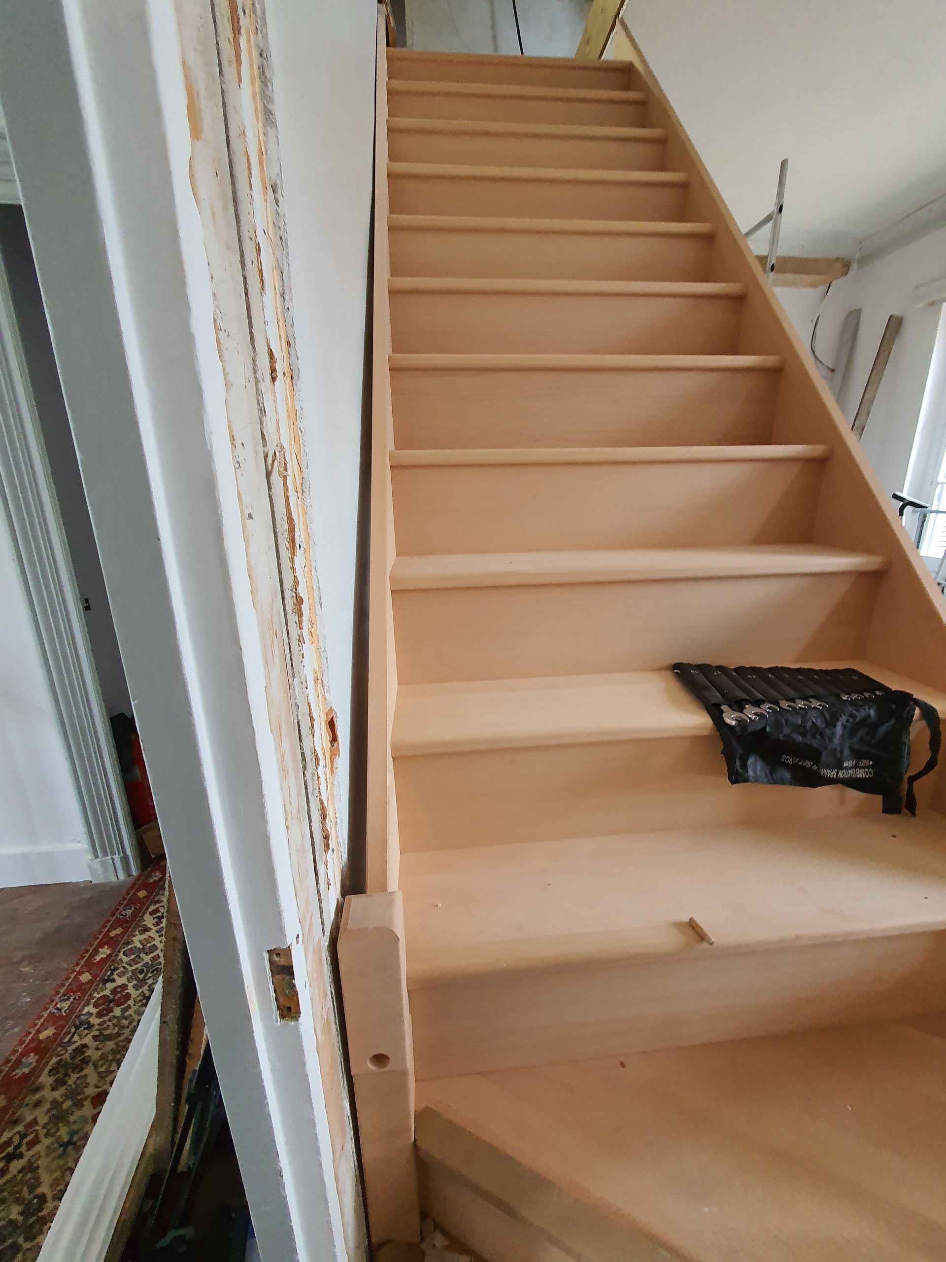 Escalier en bois droit posé contre un mur blanc