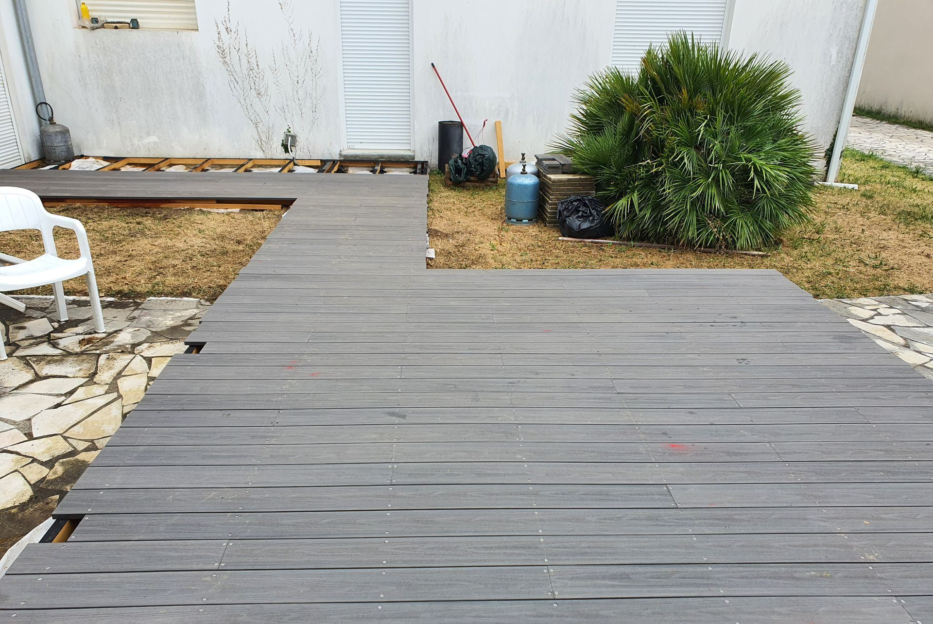 Terrasse en bois avec une chaise en plastique sur la gauche