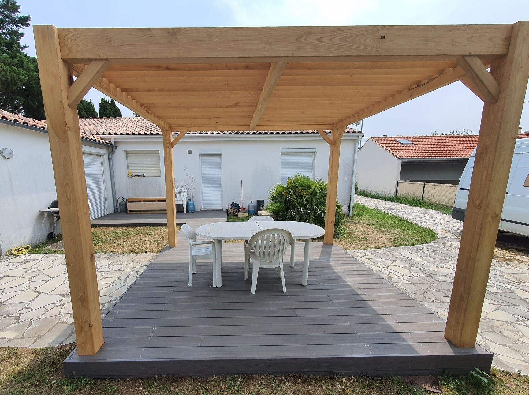 Pergola en bois avec une table et des chaises blanches