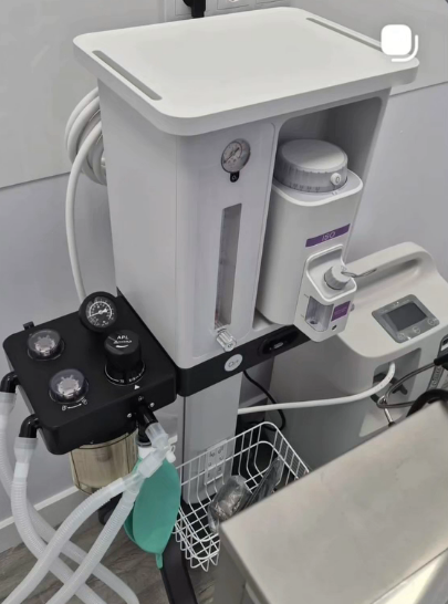 Dispositivo médico blanco con manómetros, tubos y componentes de control en un entorno clínico.