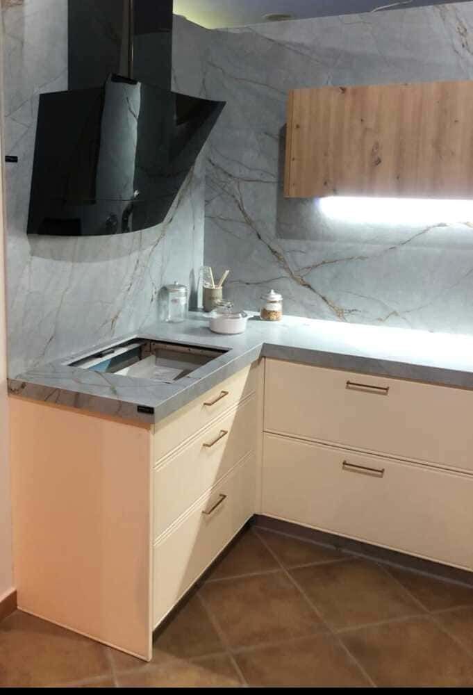 Una cocina con gabinetes blancos, un fregadero y una campana extractora.