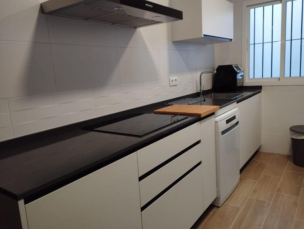 Una cocina con gabinetes blancos y encimeras negras.