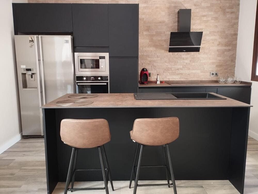 Una cocina con dos taburetes de bar y un refrigerador.