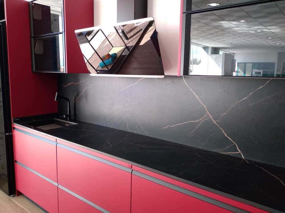 Una cocina con gabinetes rojos y encimeras negras.