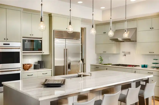 Una cocina con gabinetes blancos, electrodomésticos de acero inoxidable y una isla grande.